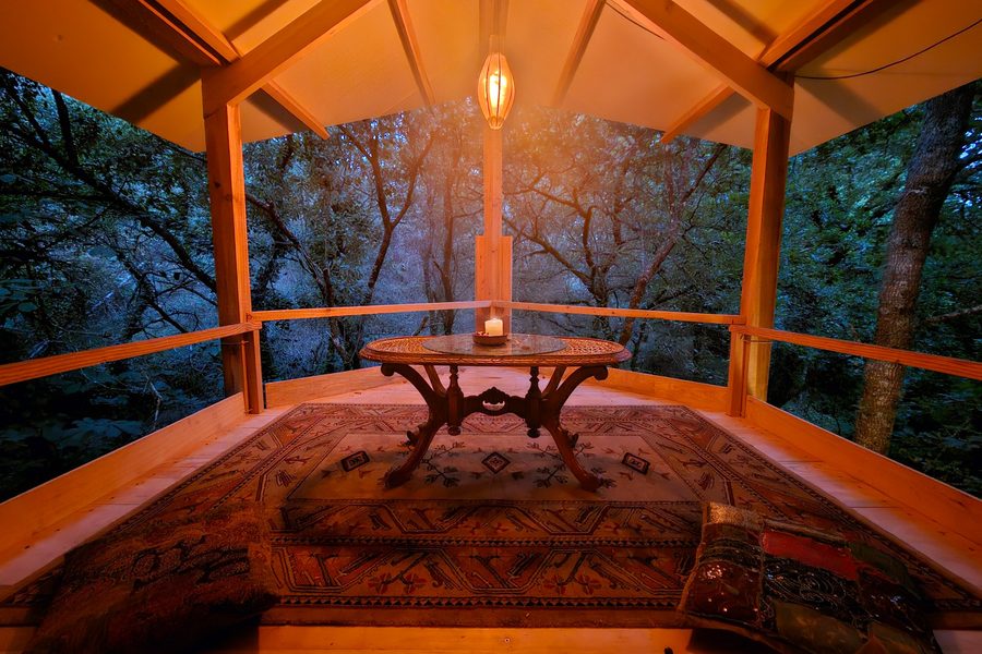 A timber room in the oak canopy under a vaulted roof, lit by a lantern